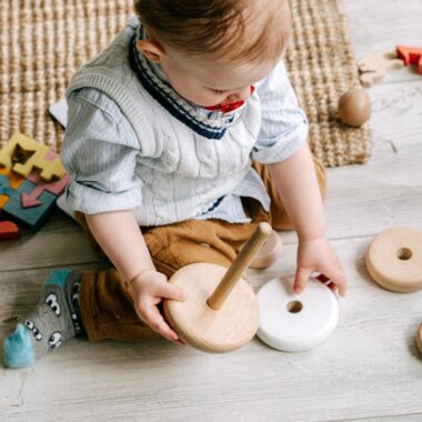 Cute toddler engaging with wooden toys on a play mat, enhancing early learning and development.
