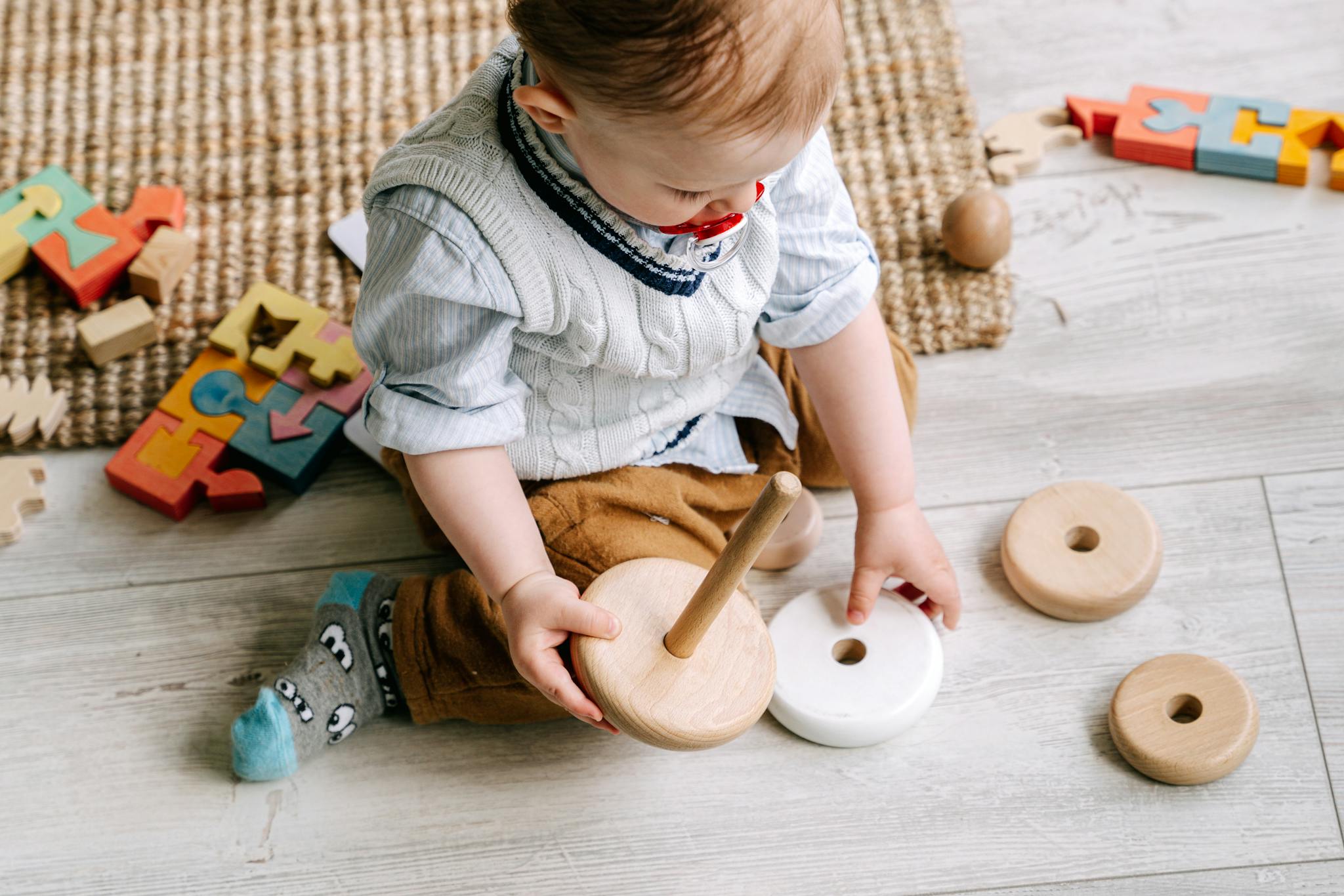 Cute toddler engaging with wooden toys on a play mat, enhancing early learning and development.